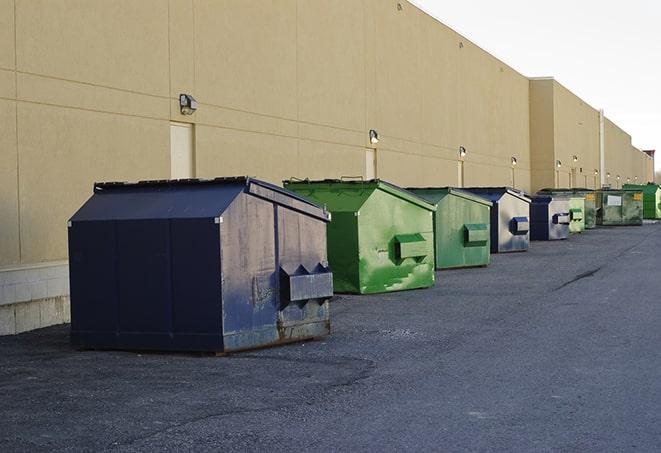 a construction worker disposing of debris into a dumpster in Broadway